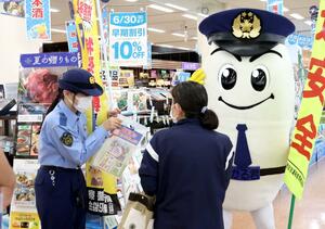 県警マスコットキャラクター「ひかるくん」や新潟西署署員が、自転車の鍵かけなどを買い物客に呼びかけた啓発活動=新潟市西区小新5