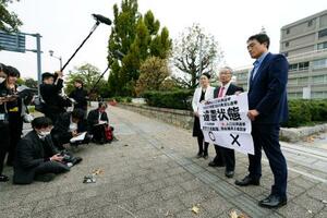 「1票の格差」訴訟の判決を受け、広島高裁前で「違憲状態」などと書かれた紙を掲げる原告側の弁護士グループ=25日午後