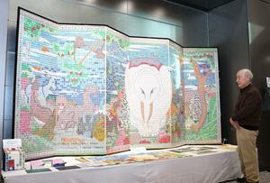 切手で作ったびょうぶ絵を見つめる岩坂薫さん=長岡市大手通1