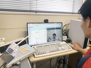 遠隔点呼システムを使い運転手(手前右)が運行管理者とモニター越しで点呼業務を行う様子=新潟市東区の新潟貨物ターミナル営業所