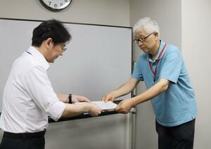 最低賃金に関する意見書を提出するえちごユニオンの髙島悟書記長(右)=18日、新潟市中央区