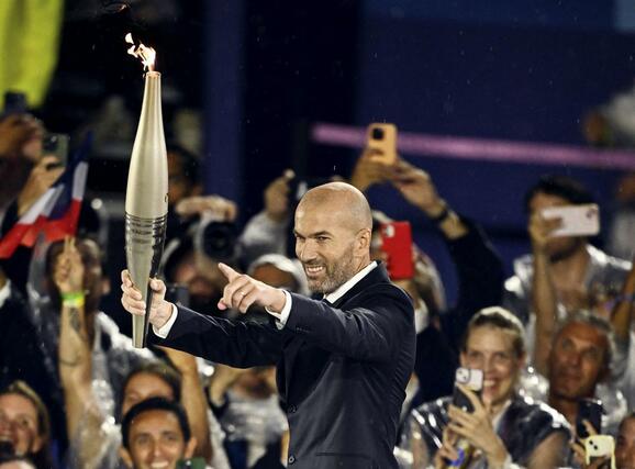 パリ五輪の開会式で聖火を掲げるサッカー元フランス代表のジダンさん＝７月２６日、パリ（ロイター＝共同）