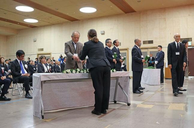 献花台に向かって列をつくる日本の招待客ら=13日、佐渡市