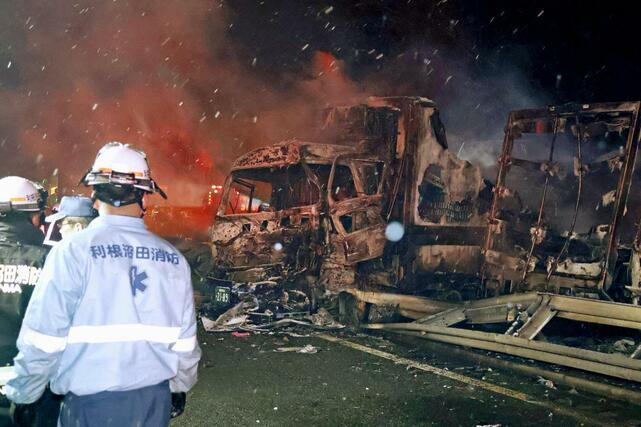 関越自動車道の事故現場で焼けた車と、活動する消防関係者ら＝２７日午前３時ごろ、群馬県みなかみ町