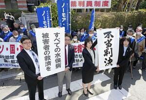 水俣病特別措置法に基づく救済策で対象外となった人たちが国などに損害賠償を求めた訴訟の判決で請求が棄却され、熊本地裁前で「不当判決」を訴える原告側の弁護士ら=3月22日午前、熊本市