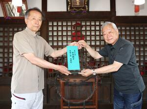 稲垣平助研究会の山岸利光代表(左)から盾を受け取る広井晃町内会長=長岡市地蔵1の地蔵尊