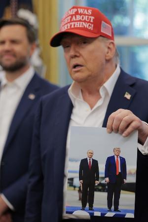 　ロシアのプーチン大統領と一緒に米アラスカ州で撮影された写真を手にするトランプ大統領＝８月２２日、ワシントン（ゲッティ＝共同）