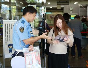 長岡署の署員らが木彫りペン立てなどを配り交通事故防止を呼びかけた=長岡市上前島1