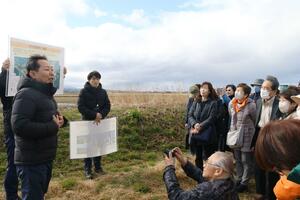 視察で訪れた佐渡側のトキガイドらに、認証制度の取り組みを説明する濱田栄治代表（左）＝３月、石川県羽咋市
