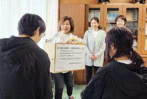 塩沢小の児童に手作りのコサージュを手渡す南魚沼商工会女性部の部員=南魚沼市塩沢