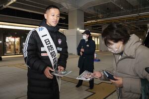 防犯や交通安全を呼びかけるチラシが入った袋を配るアルビレックス新潟の小野裕二選手=12月13日、新潟市中央区