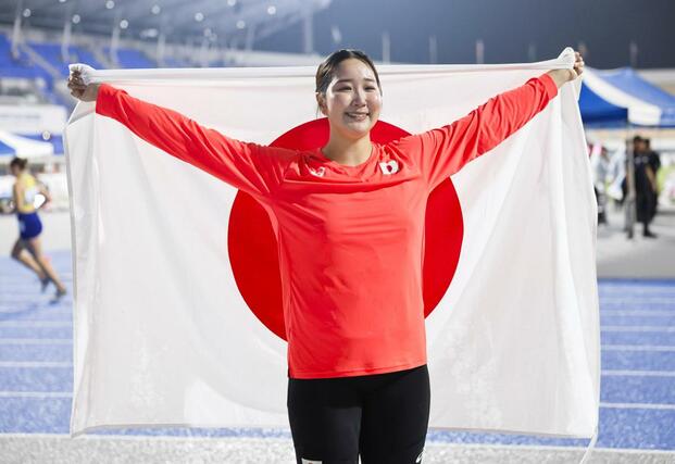 女子円盤投げで３位となり、日の丸を掲げる郡菜々佳＝亀尾（共同）