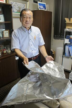遮熱シートを手にするサンユー印刷の玉木敏会長=三条市