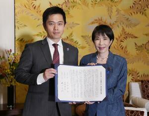 署名した連立政権合意書を報道陣に示す自民党の高市総裁(右)と日本維新の会の吉村代表=20日午後、国会