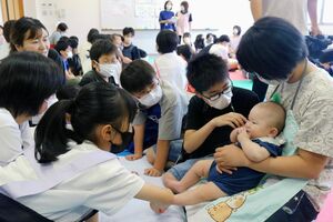 赤ちゃんと触れ合う児童たち=佐渡市千種