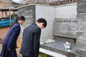 小川未明の生家跡に立つ石碑に花を供えた参加者＝５日、上越市幸町