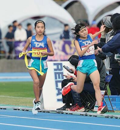 十日町南の1区村山椛(右)が2区田村爽にたすきを渡す=7日、新発田市五十公野公園