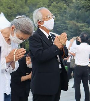 慰霊碑の前で手を合わせる飯田國彦さん。亡き家族に平和を誓った=6日、広島市中区の平和記念公園