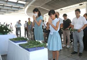 追悼式で長崎原爆の犠牲者に花を手向ける参列者=9日、新潟市中央区