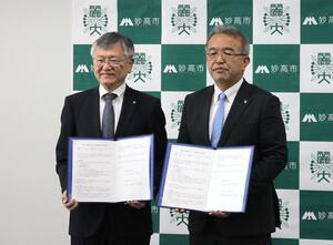 協定書を手にする妙高市の城戸陽二市長(右)と麗沢大の徳永澄憲学長=妙高市役所
