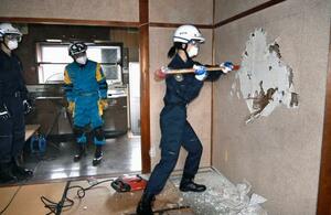 訓練で岐阜羽島署の旧署長官舎の土壁を壊す警察官=15日午前、岐阜市