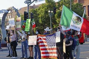 米国やメキシコの国旗を掲げ、移民取り締まりに抗議する人々=8日、ロサンゼルス
