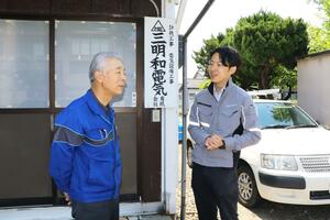 三明和電気の本間利夫取締役(左)と、同社をグループに受け入れた石崎防災電設の堀内慶大社長=新潟市中央区