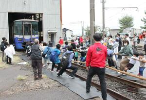 鉄道車両を引っ張る綱引きに挑戦する親子連れら=11日、上越市の直江津D51レールパーク