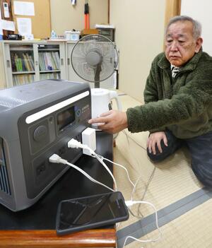 柏崎市が町内会単位で配備した蓄電池を使う猪俣元英さん=柏崎市安田