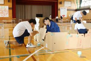 段ボールを使い、避難スペースの間仕切りを作る中野小屋中の生徒たち=新潟市西区中野小屋