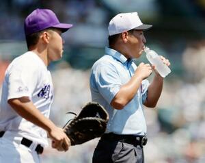 19日、関東第一―日大三戦の7回を終えて給水する一塁塁審=甲子園球場