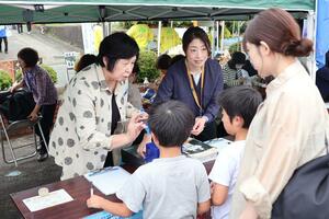 拉致被害者救出へ協力を呼びかけ、署名活動をする曽我ひとみさん(左)=5日、佐渡市新穂瓜生屋