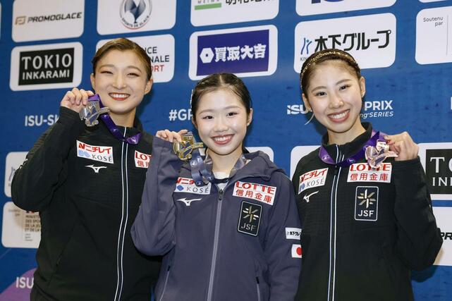 フィギュアスケートのグランプリシリーズ開幕戦フランス大会で優勝し、メダルを掲げる中井亜美。左は２位の坂本花織、右は３位の住吉りをん＝１８日、アンジェ（共同）
