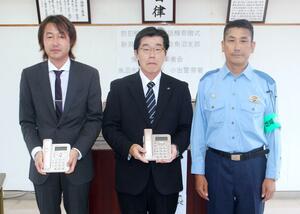 防犯機能付き電話機を寄贈した横山和彦・県建設業協会魚沼支部長(中央)と、浅井一久・魚沼市建設業者会会長(左)=小出署
