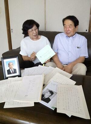 故山﨑徹爾さんの写真と、「死ぬんじゃない生きるんだ!!」と題した直筆の手記。長男の山﨑徹さん(右)夫妻が冊子にまとめた=上越市