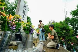 日航機墜落事故現場の尾根に立つ「昇魂之碑」で手を合わせる遺族=12日午前、群馬県上野村