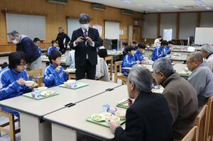 犯罪者の更生などを学ぼうと育てたサツマイモを食べる中学生と保護司ら=村上市府屋