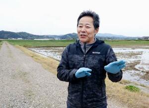 トキの餌場として期待される水田の前で取材に応じる浜田栄治さん=4月、石川県羽咋市