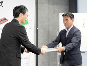 朝日田智昭常務理事(右)から決定書を受け取る鈴木力市長=燕市役所