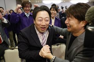 選対の仲間らと当選を喜び合う内山航（中央）＝８日、新潟市中央区