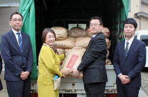 山下浩子会長(左から2人目)に玄米1トンを寄贈する組合青年部部長の関口真也さん(同3人目)ら=三条市北新保1