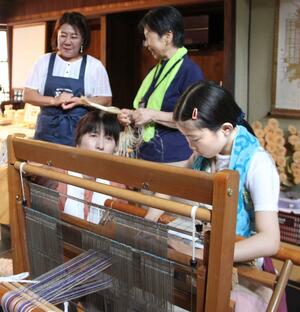 カラムシの繊維を使った機織りを体験する参加者=上越市の旧今井染物屋