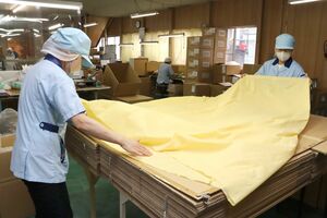 リリーの代表的な商品「ディスポ(使い捨て)防炎カーテン」をたたむ従業員。日本初の製品として、特許を取得している=新潟市東区豊3