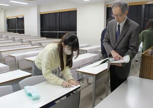 受験番号が書かれたシールを貼り、設営を進める新潟大の職員＝１６日、新潟市西区