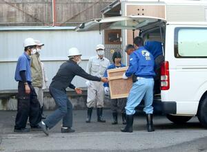 分散飼育地から移送されてきたトキが入った箱を、慎重に施設へ運び込む職員=27日、佐渡市新穂長畝