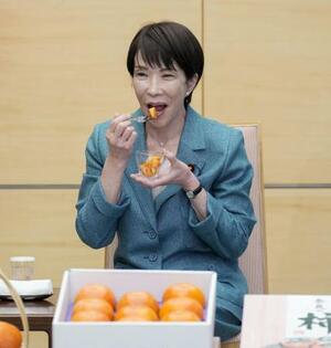 　贈呈された奈良県特産の柿を試食する高市首相＝１９日、首相官邸