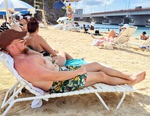 真夏日となった那覇市の「波の上ビーチ」でくつろぐ外国人観光客ら=17日午後