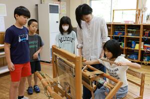 機織り機を使い、羽越しな布作りに取り組む子どもたち=村上市勝木