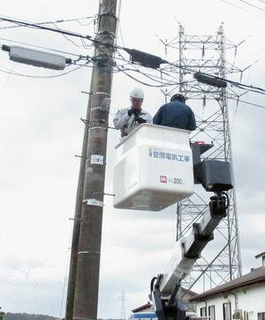 電柱に防犯灯を設置する中条高校の生徒ら＝胎内市
