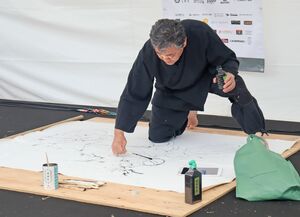 墨と割り箸を使ってオートバイの絵を描く遠藤信さん=南魚沼市下一日市